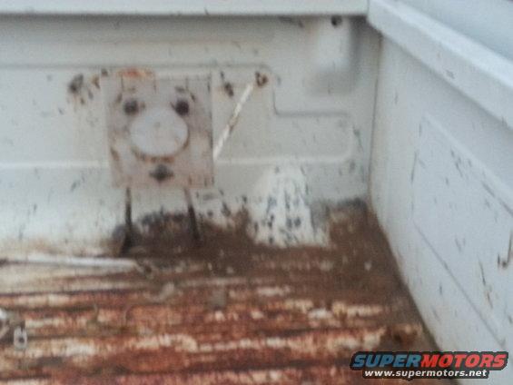 White truck bed interior with rust on the floor and a metal bracket with two holes