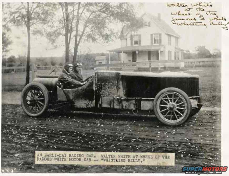 Racing car with two occupants, side view. Dark body, spoked wheels