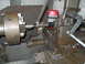 1992 Ford Bronco - A close-up view of a part being machined on a lathe, with a wrench in operation and a red weather radio visible.
