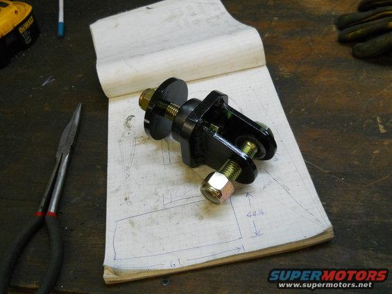 Black metal automotive part with bolts on a notebook with a diagram and measurements