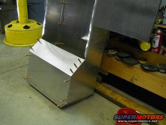 Metal fabrication project with visible rivets and unfinished edges