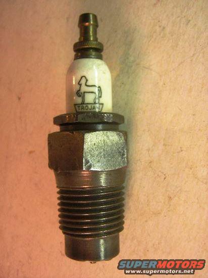 Spark plug with white ceramic insulator, black horse logo, and "TROJAN" text