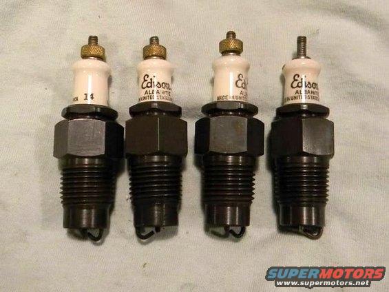 Four Edison spark plugs with white ceramic tops and black metal bases