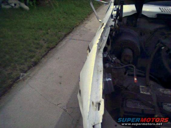 Damaged white vehicle engine bay with visible Supermotors.net logo