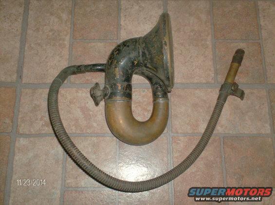 Vintage phonograph horn and flexible tube on a tiled floor