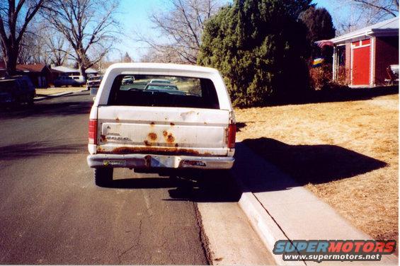 White Ford Bronco parked on street, showing rust on tailgate