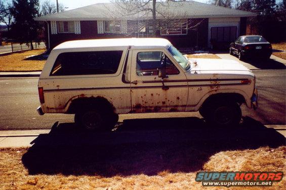 White 1978 Ford Bronco with extensive rust damage on the lower body panels, seen from the side