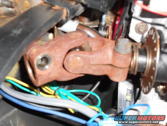 Rusted steering universal joint with blue, yellow, and green wires