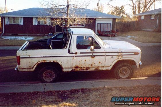 White Ford Bronco with significant rust on the lower body panels, parked curbside