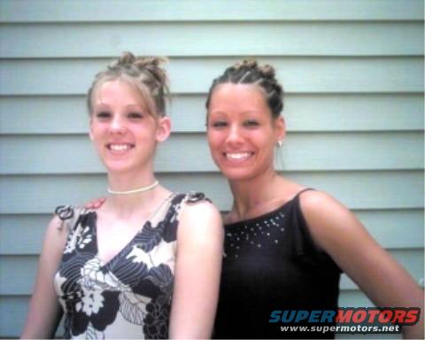 Two women smiling in front of a paneled wall