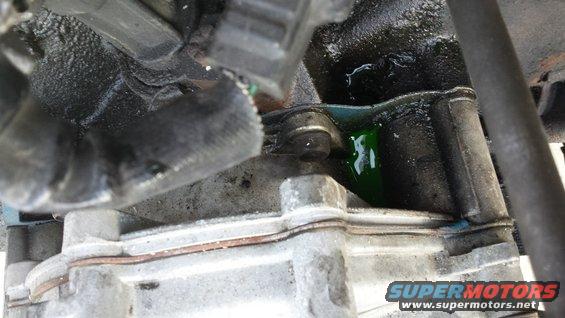Engine block with green fluid leaking from a hose connection