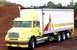 1999 Ford Crown Victoria - A yellow box truck is parked outdoors with a large pile of mulch behind it.