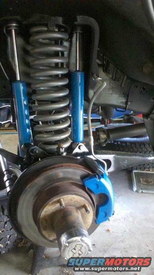 Close-up of a vehicle's front suspension with blue shocks and brake caliper