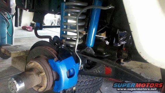 Front suspension with blue brake caliper and shock absorber, rusty brake rotor, and tire