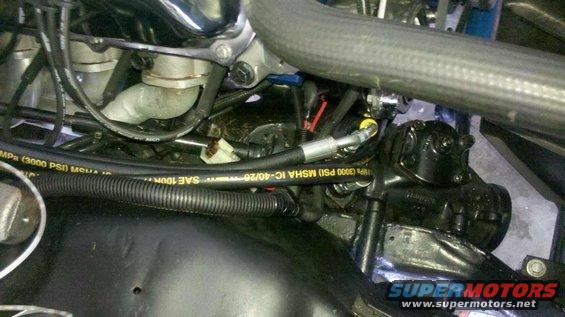 Close-up of engine bay showing hoses, steering gear, and engine parts. Text on hose reads 'IC-40/26 MSHA IC-40/26 SAE 100R7 3000 PSI'