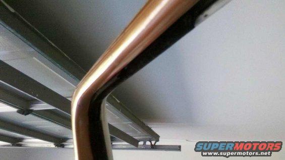 Curved chrome trim piece against a white ceiling and metal beams