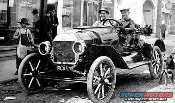 1909 Ford Model T speedster with two men in hats driving, boy in overalls standing nearby