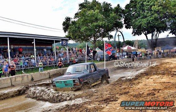 Dark blue Ford F-Series pickup truck with green grille in mud pit
