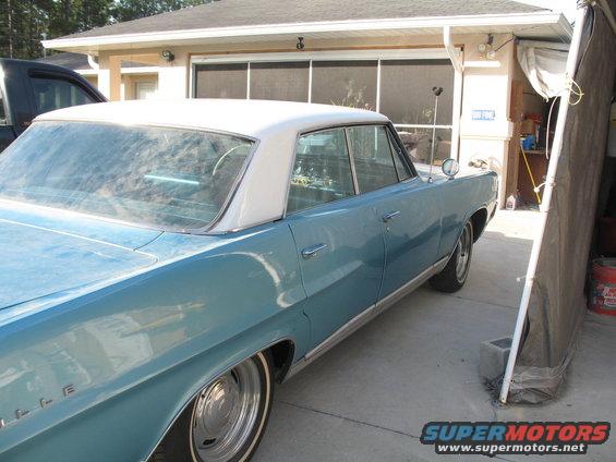 Blue sedan with a white vinyl roof, seen from the rear quarter, parked in a driveway