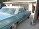 1972 Ford Ranchero - A blue sedan with a white roof is parked in front of a garage, with another vehicle partially visible.