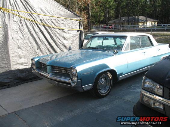 Light blue 1963 Pontiac Bonneville parked next to a black pickup truck