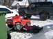 1986 Ford Bronco - A dark green Ford Bronco is parked in the snow, with a person lying on a sled underneath a red toy truck.