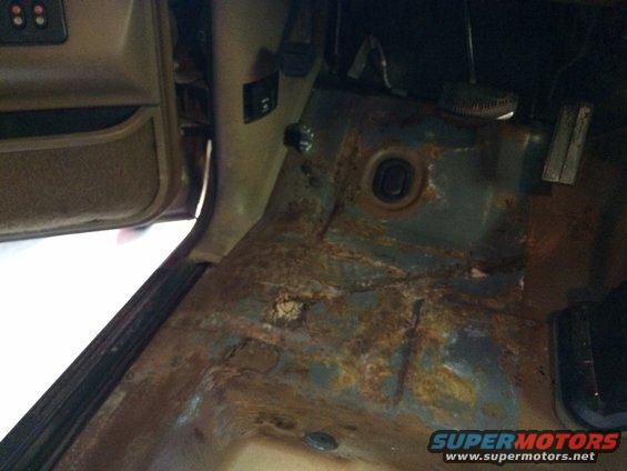 Rusted floor pan and lower door jamb inside a vehicle