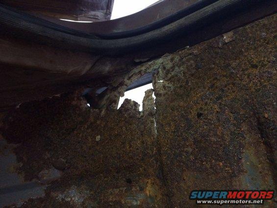 rusted out floor pan of a vehicle, showing holes and damage