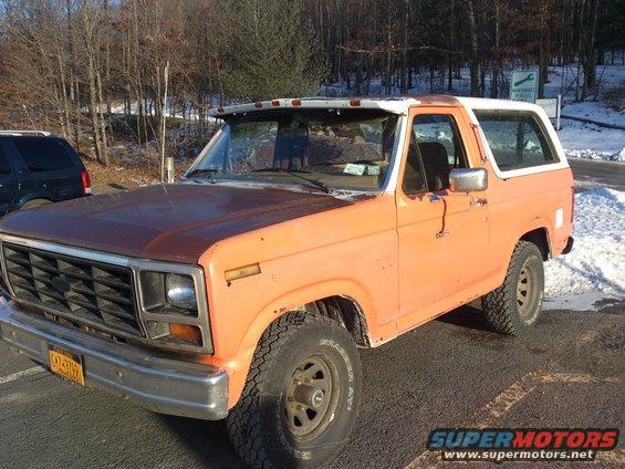 1986 Ford Bronco, orange with white top, parked outdoors