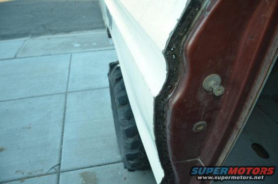 close-up of a vehicle's door frame and a large tire