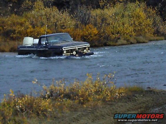 Dark blue 1979 Ford F-Series pickup truck driving through river
