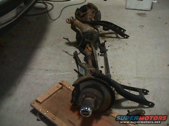 Disassembled front axle assembly with brake rotor and hub on a wooden platform