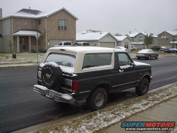1992 Ford Bronco parked on street with snow on ground and roofs