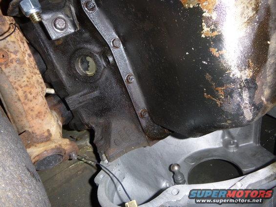 Close-up of a rusty exhaust manifold and a greasy engine oil pan