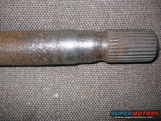 rusted metal shaft with splines on a textured surface