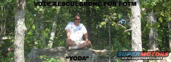 Man in white t-shirt and shorts sits cross-legged on a rock outdoors, with trees and foliage in the background. Text reads "VOTE RESCUEBRONC FOR FOTM" and "YODA"