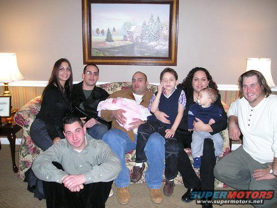 Family posing on a floral couch in front of a painting