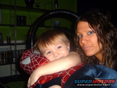 Woman and child with Spider-Man toy, indoor scene with shelves and a steering wheel