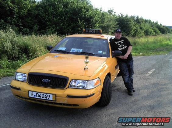 Yellow 2006 Ford Crown Victoria taxi with a trophy on the hood