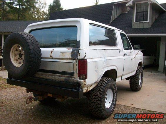 White Ford Bronco, lifted, with spare tire mounted on rear bumper. Visible rust on body panels