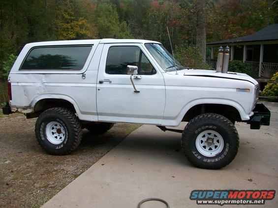 White lifted SUV with side pipes, 3q-front view. Appears to be from the early 1980s