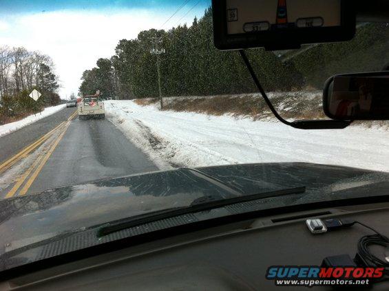 White pickup truck on snowy road, viewed from inside a vehicle