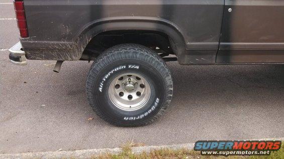 Rear wheel and fender of a dark-colored SUV, possibly a Ford Bronco
