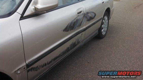 Side view of a car door with a large scratch and a painted-on butterfly graphic