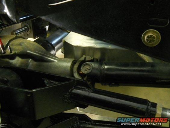 Close-up of a driveshaft connected to a differential housing, with visible Supermotors.net watermark