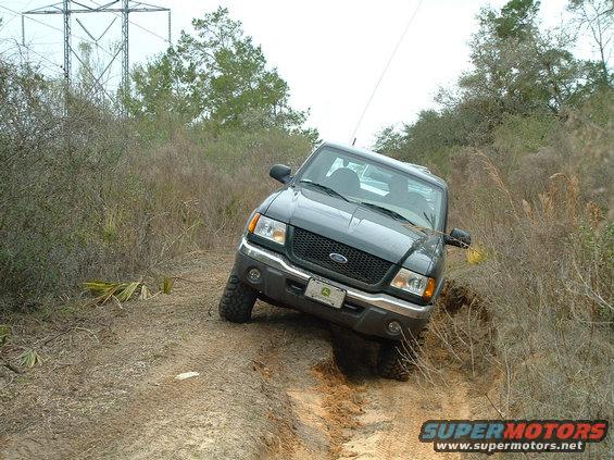 Dark gray Ford Ranger pickup truck driving off-road on a dirt path, tilted to the side