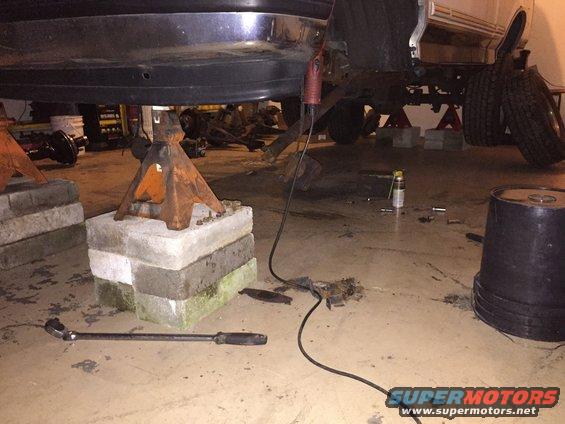 Vehicle chassis on jack stands with tools on the floor