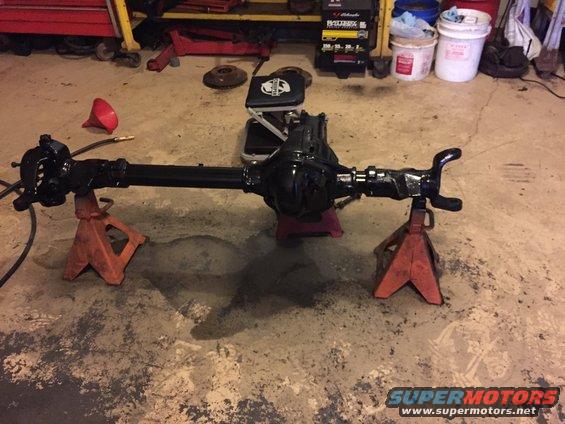 Rear axle assembly on orange jack stands in a garage