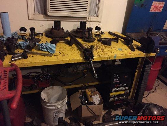 Workbench with assorted vehicle parts including hubs, rotors, and driveshaft