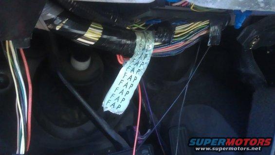 Close-up of a vehicle's wiring harness with a white tape label repeating 'FAP'
